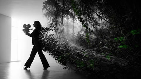 3D render of a woman walking through hyper-realistic enchanted forest with glowing particles.