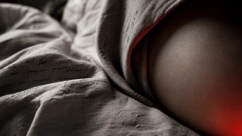 A sensual nude figure reclines on silk sheets in a dimly lit bedroom, soft lighting highlighting curves.